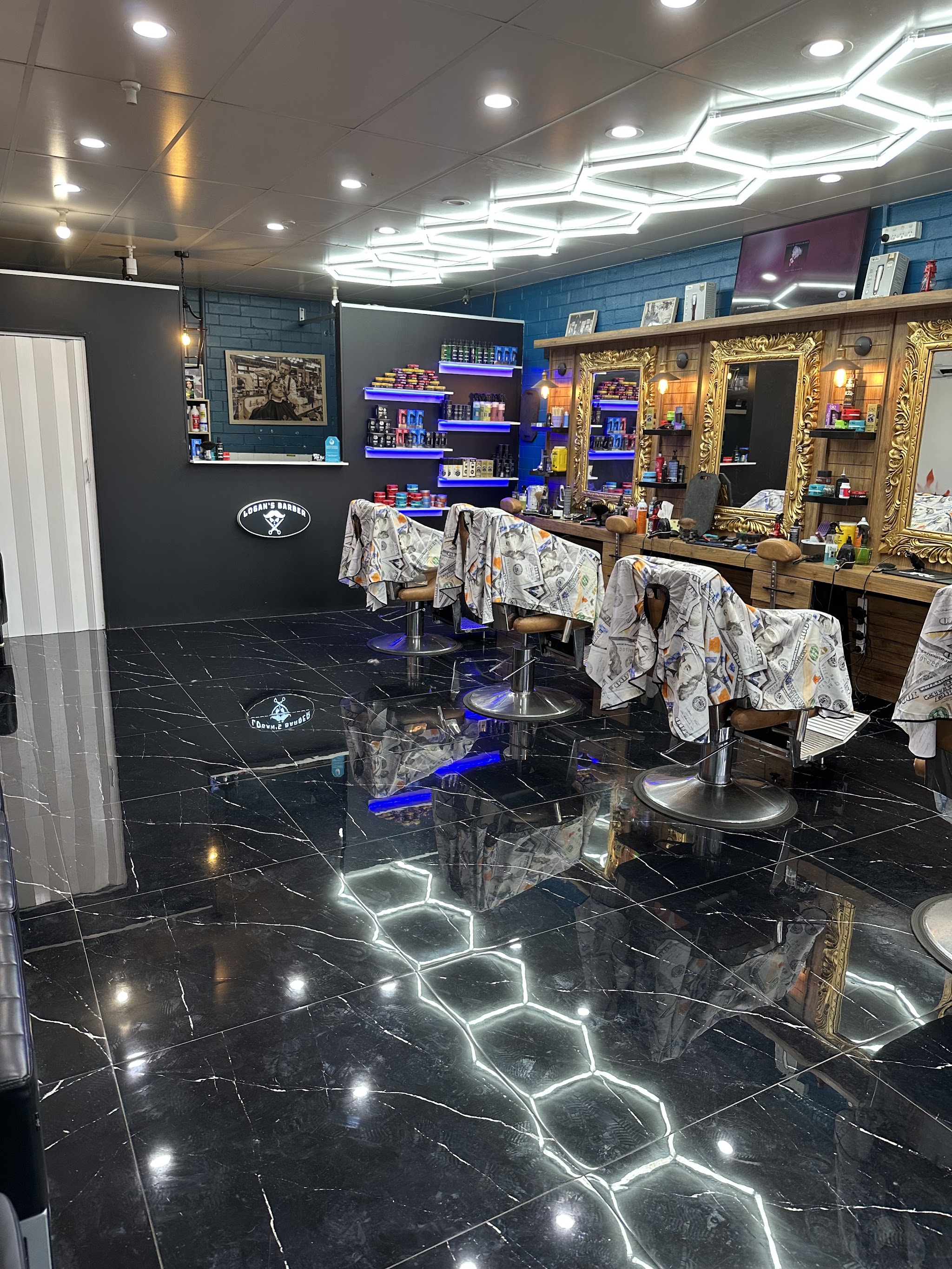 Inside Logan's Barber: a row of barber chairs, gold framed mirrors and a hexagon LED ceiling over a black marble floor