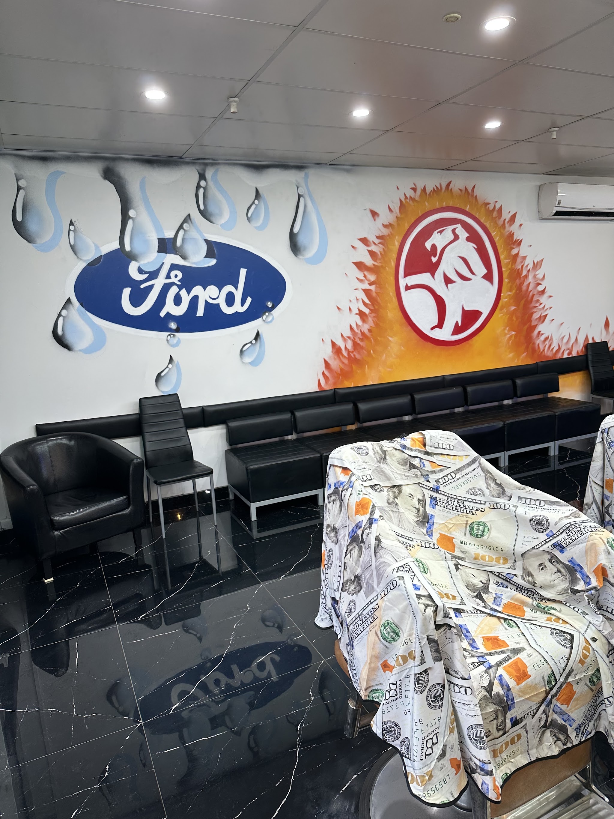 The waiting area: black leather bench seating under a painted Ford and Holden mural